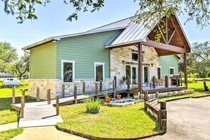 A green building with a stone facade, a covered porch, and a grassy yard.