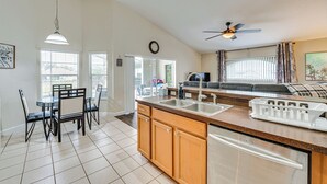 A spacious kitchen with a central island, a dining area with chairs, and a living room with a sofa and a ceiling fan. - 11 Mi to Disney: Family-friendly Home in Davenport (Davenport)