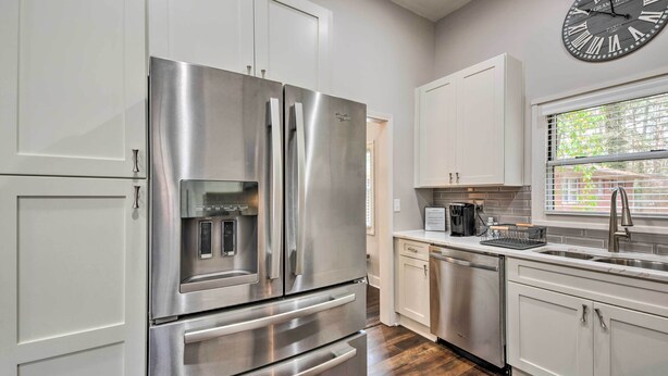 A modern kitchen with stainless steel appliances, white cabinetry, and a large wall clock. - Atlanta Retreat w/ Deck in Greenbriar Area! (Atlanta)