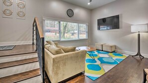 A living room with a sofa, a coffee table, a colorful rug, a ceiling fan, and a window with blinds. - Atlanta Retreat w/ Deck in Greenbriar Area! (Atlanta)