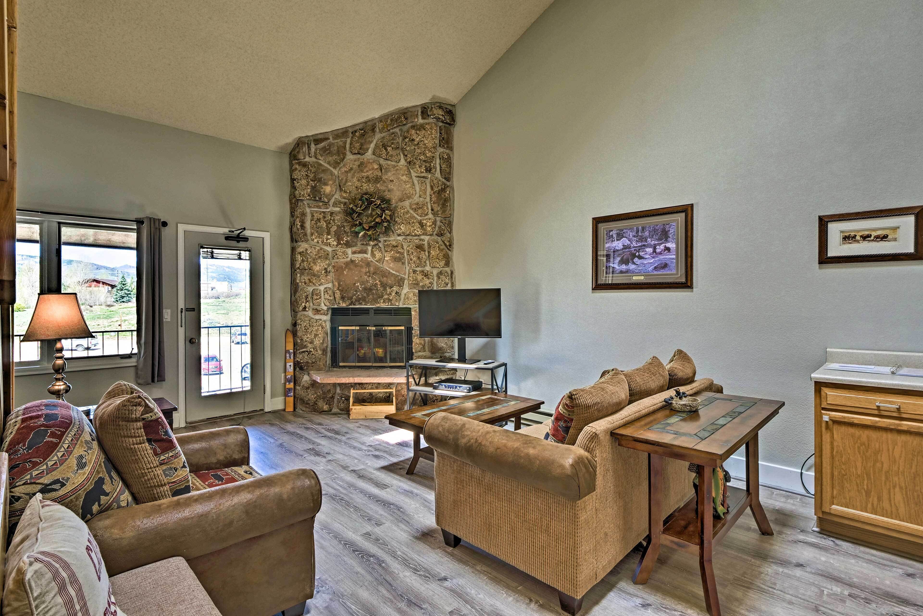 A living room with a stone fireplace, a television, and a dining area.