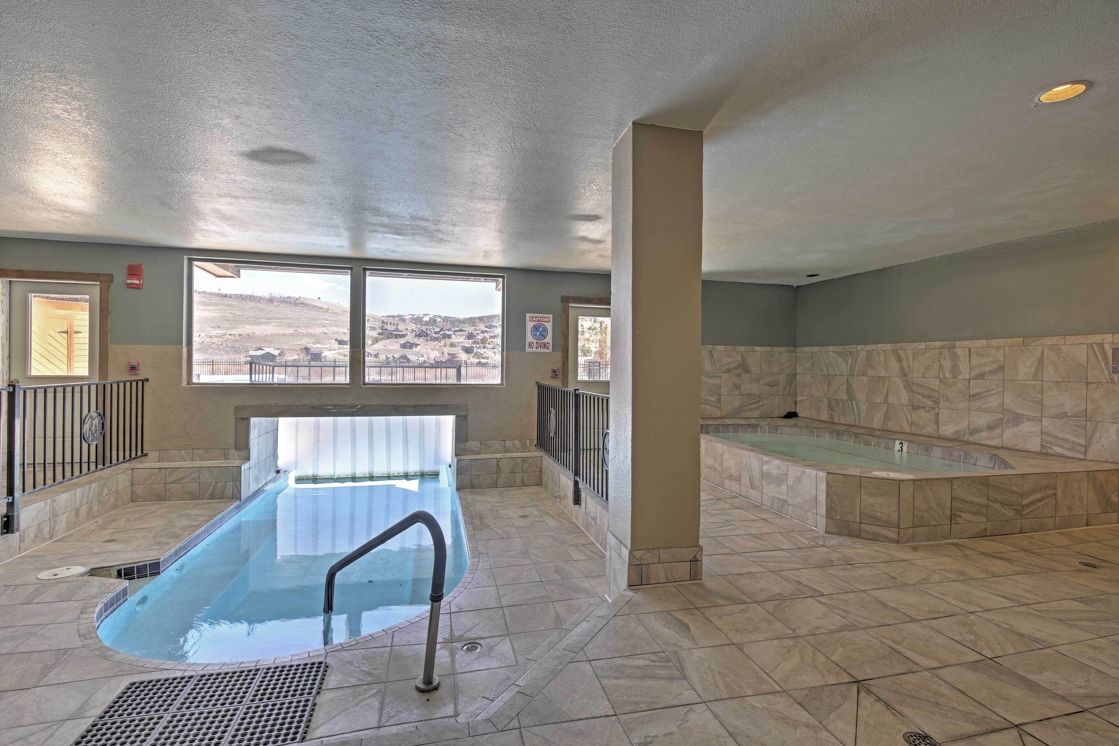 Ein Hallenbad mit Blick auf eine hügelige Landschaft, ein Whirlpool und ein Fliesenboden.