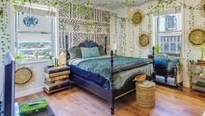 A bedroom with a four-poster bed, a large window with a view, and decorative wall hangings. - Colorful Atlanta Vacation Rental - Walk to Dtwn! (Atlanta)