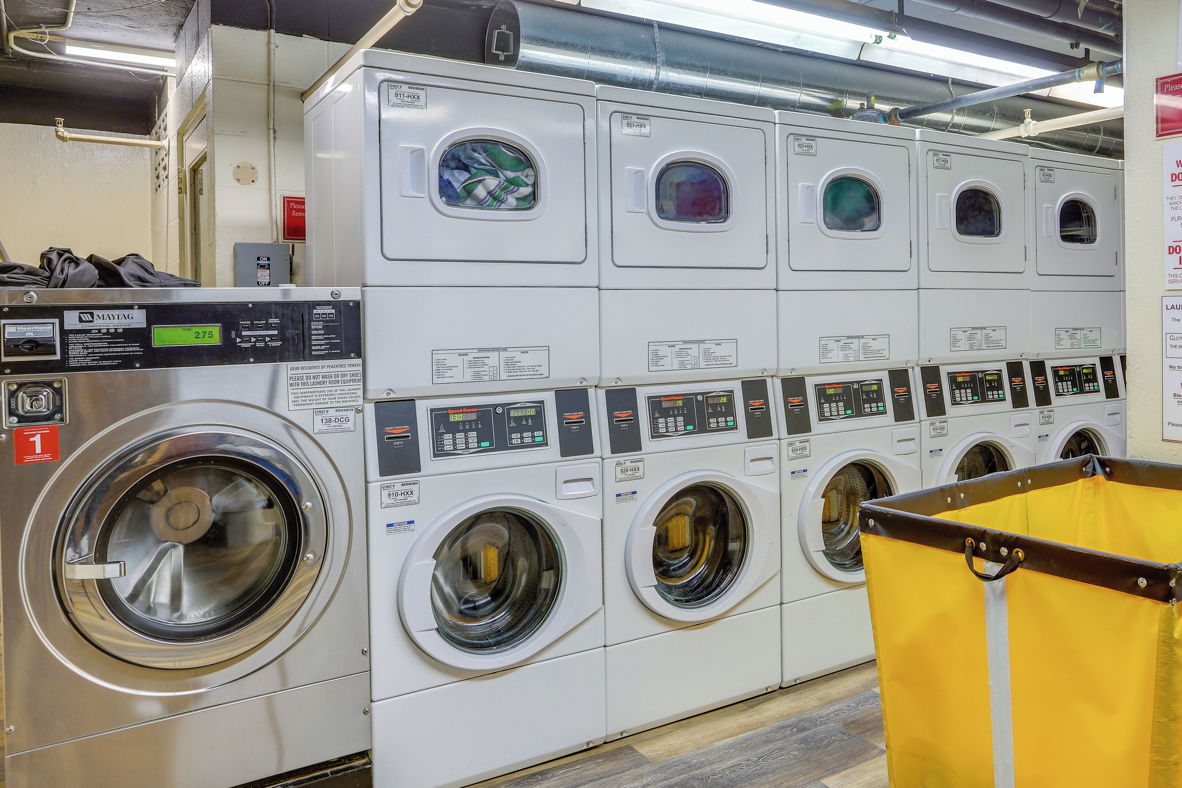 A row of stacked front-loading washing machines in a commercial laundry facility.