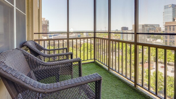 A balcony with wicker furniture and a view of the cityscape. - Colorful Atlanta Vacation Rental - Walk to Dtwn! (Atlanta)