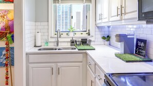 A modern kitchen with white cabinets, a built-in sink, and a window with a city view. - Colorful Atlanta Vacation Rental - Walk to Dtwn! (Atlanta)