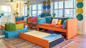 A vibrant living room with a sofa bed, colorful cushions, and a large window with circular decorations. - Colorful Atlanta Vacation Rental - Walk to Dtwn! (Atlanta)
