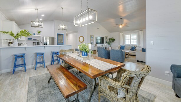 A spacious kitchen with a wooden dining table, blue bar stools, and a hanging light fixture. - Private Pool & Furnished Deck: Port Aransas Home! (Port Aransas)
