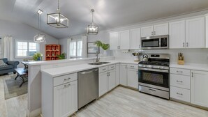 A modern kitchen with white cabinetry, stainless steel appliances, and pendant lighting. - Private Pool & Furnished Deck: Port Aransas Home! (Port Aransas)