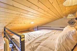 Ein Schlafzimmer mit Holzbalkendecke, einem Bett mit weißer Bettwäsche und einem Deckenventilator.