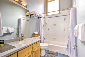 Ein Badezimmer mit Waschbecken, Toilette und Badewanne, ausgestattet mit Spiegel, Handtuchhalter und dekorativen Fliesen.