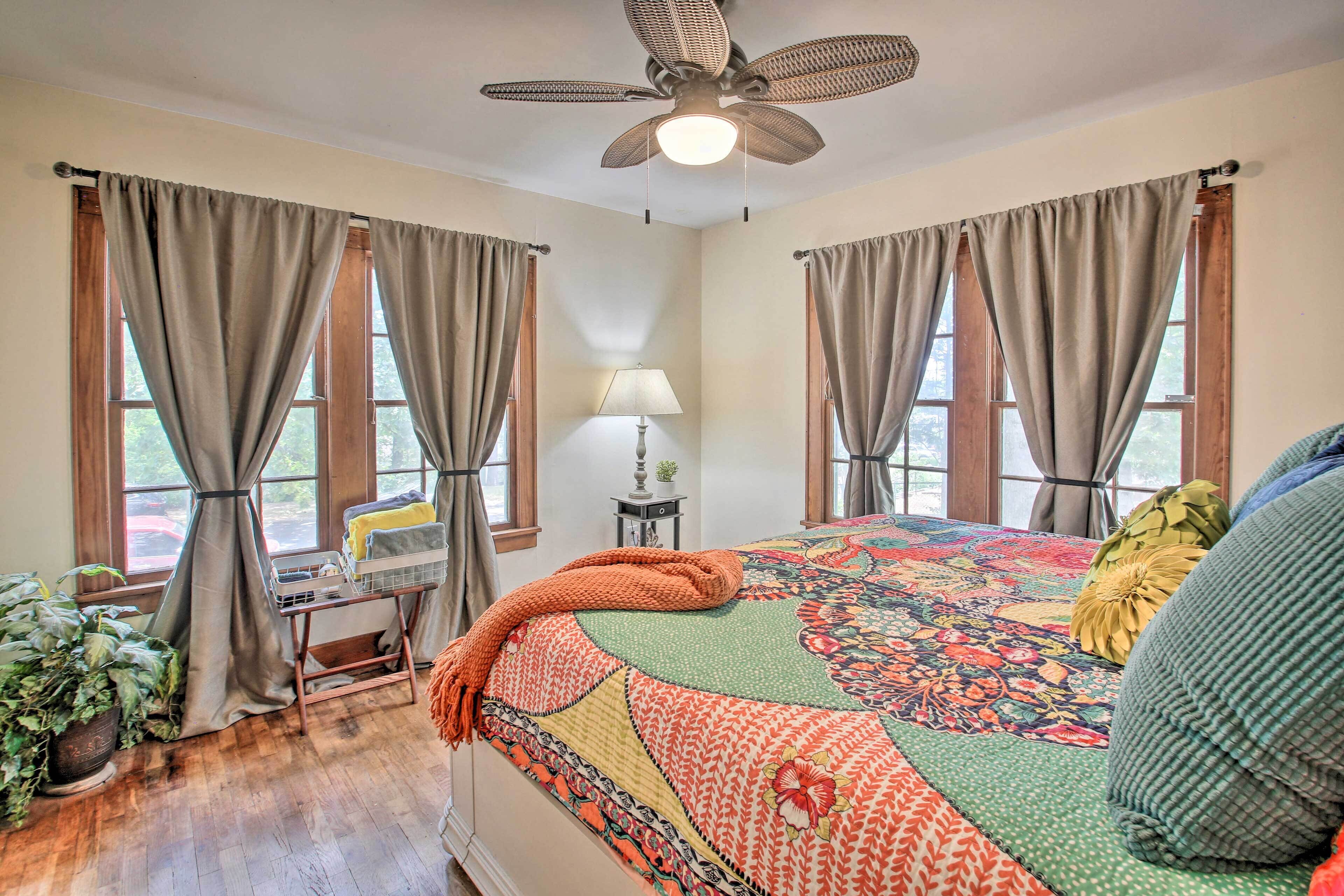 A bedroom with a large bed, a desk, and a ceiling fan.