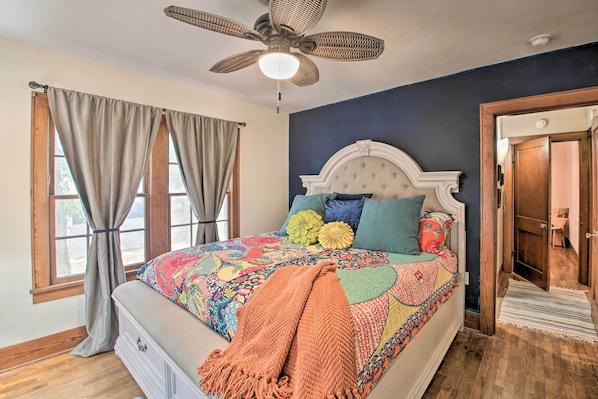 Quarto com uma cama grande, um ventilador de teto e vista para o exterior através de uma janela.