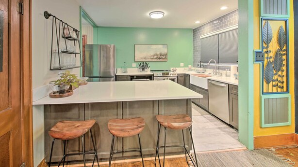 A modern kitchen with a central island, bar stools, a refrigerator, and a sink. - 2 Mi to Central Ave: Quaint Hot Springs Home! (Hot Springs)