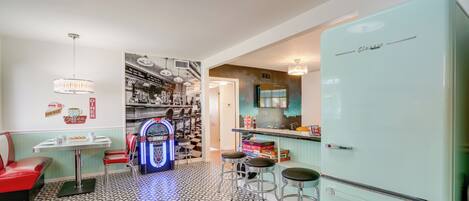 Eine Retro-Diner-Kneipe mit einem Vintage-Kühlschrank, Sitzbänken und Spielautomaten.