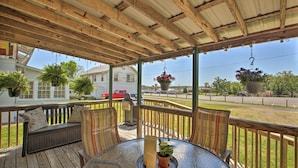 A covered outdoor seating area with a round table, benches, and hanging planters. - Hot Springs Home - Walk to Oaklawn Casino! (Hot Springs)