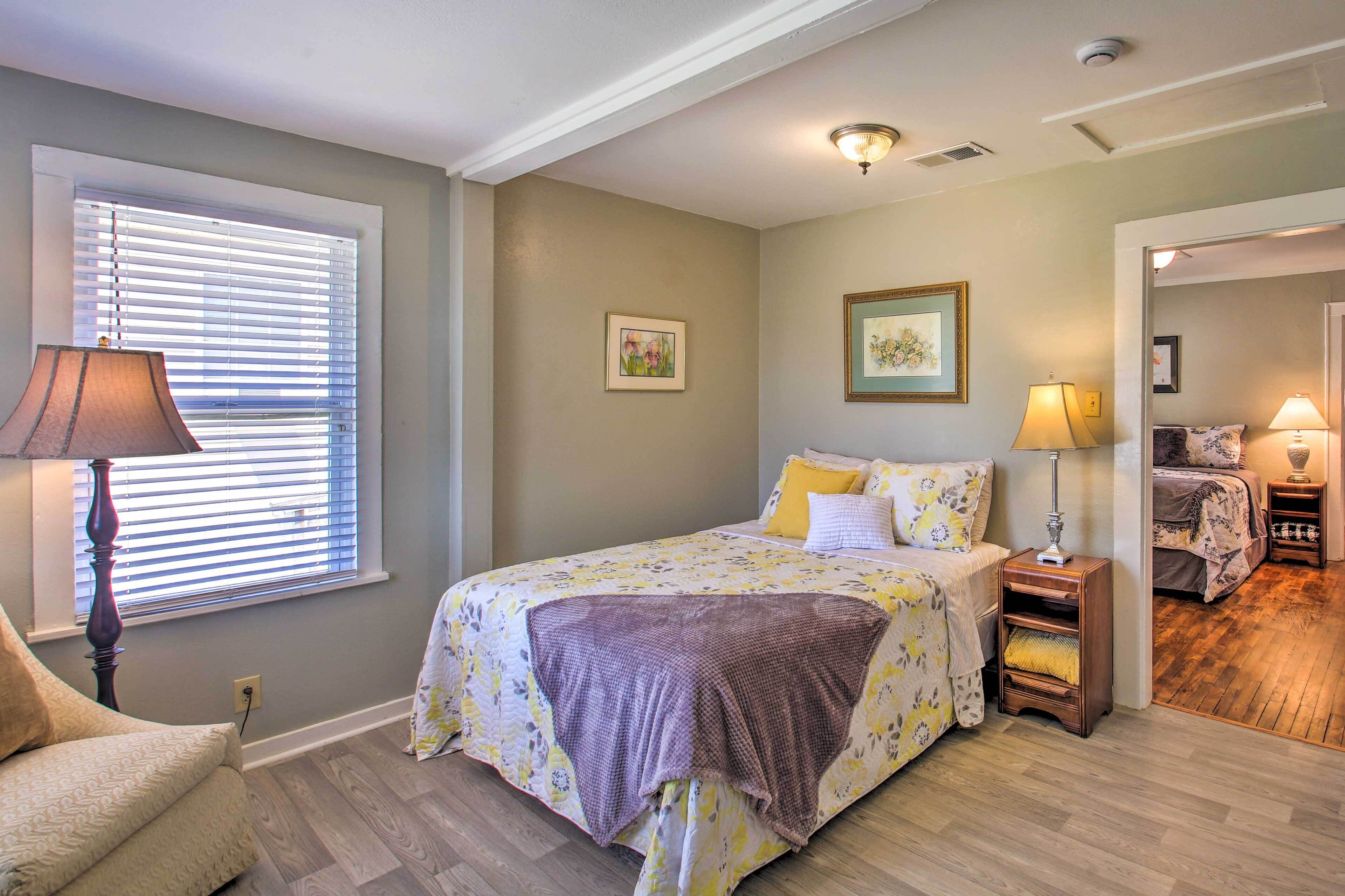 A bedroom with a bed, bedside tables, a lamp, and a window with blinds.