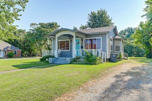 A single-story house with a porch, a front yard, and a gravel driveway. - The Green Room-amazing Musical Abode! (Tulsa)