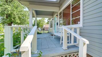 A covered porch with a white railing, a bench, and a mailbox.