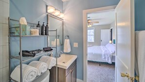 A bathroom with a sink, mirror, shelves with toiletries, and a towel rack. - Amazing Musical Abode in Expo Square Neighborhood! (Tulsa)