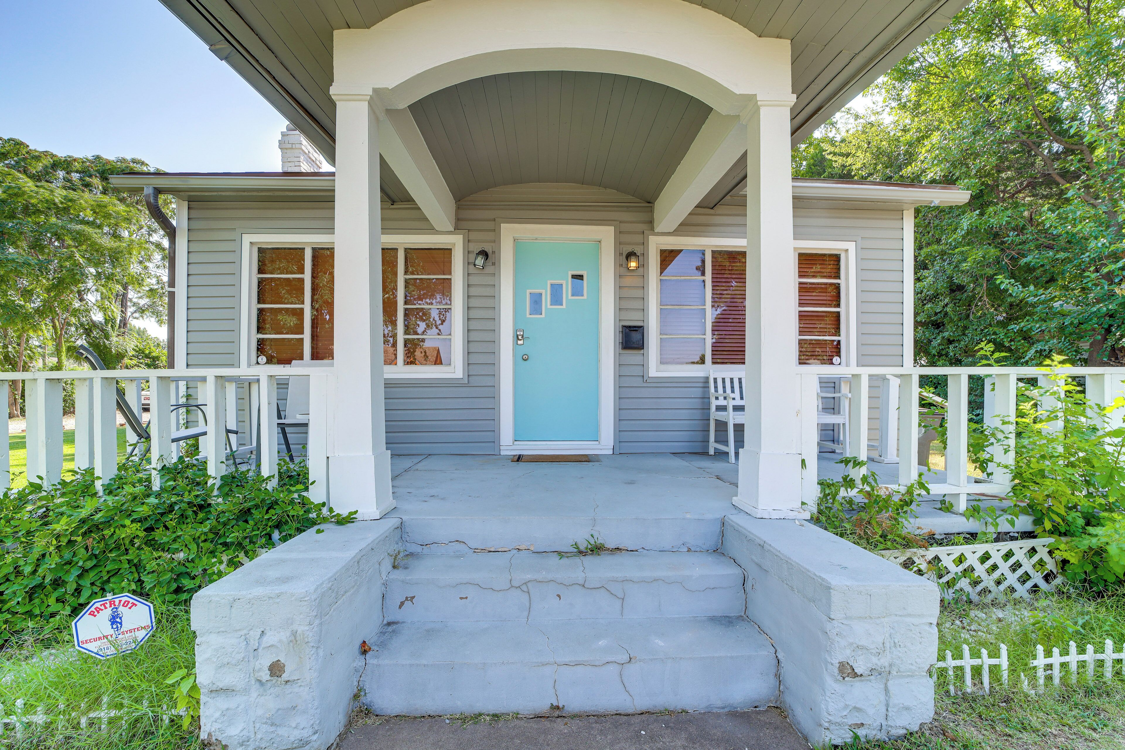 Una casa con portico, una porta blu e un recinto di legno bianco.