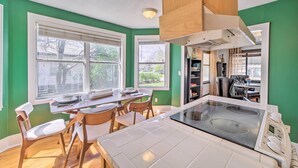 A modern kitchen with a central island, wooden chairs, and a dining table. - Amazing Musical Abode in Expo Square Neighborhood! (Tulsa)