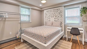 Een slaapkamer met een bed, een wit bureau, een plafondventilator en een radiator.