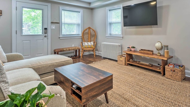 Een woonkamer met een bank, salontafel, rieten fauteuil, televisie en een open haard.