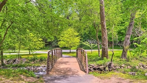 Een houten brug in een park met een verhard pad erheen.
