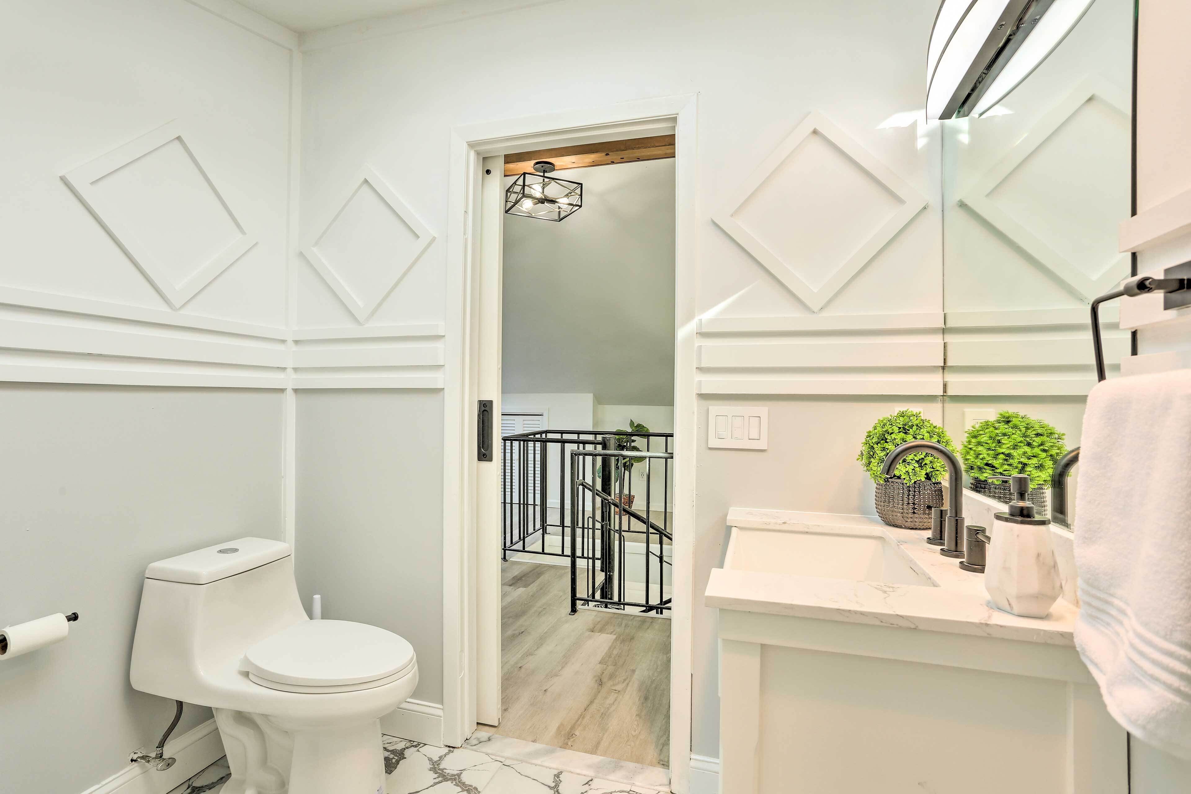 A modern bathroom with a toilet, sink, and a mirror.