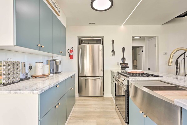 Una cocina moderna con un refrigerador de acero inoxidable, una estufa a gas y una encimera de mármol.