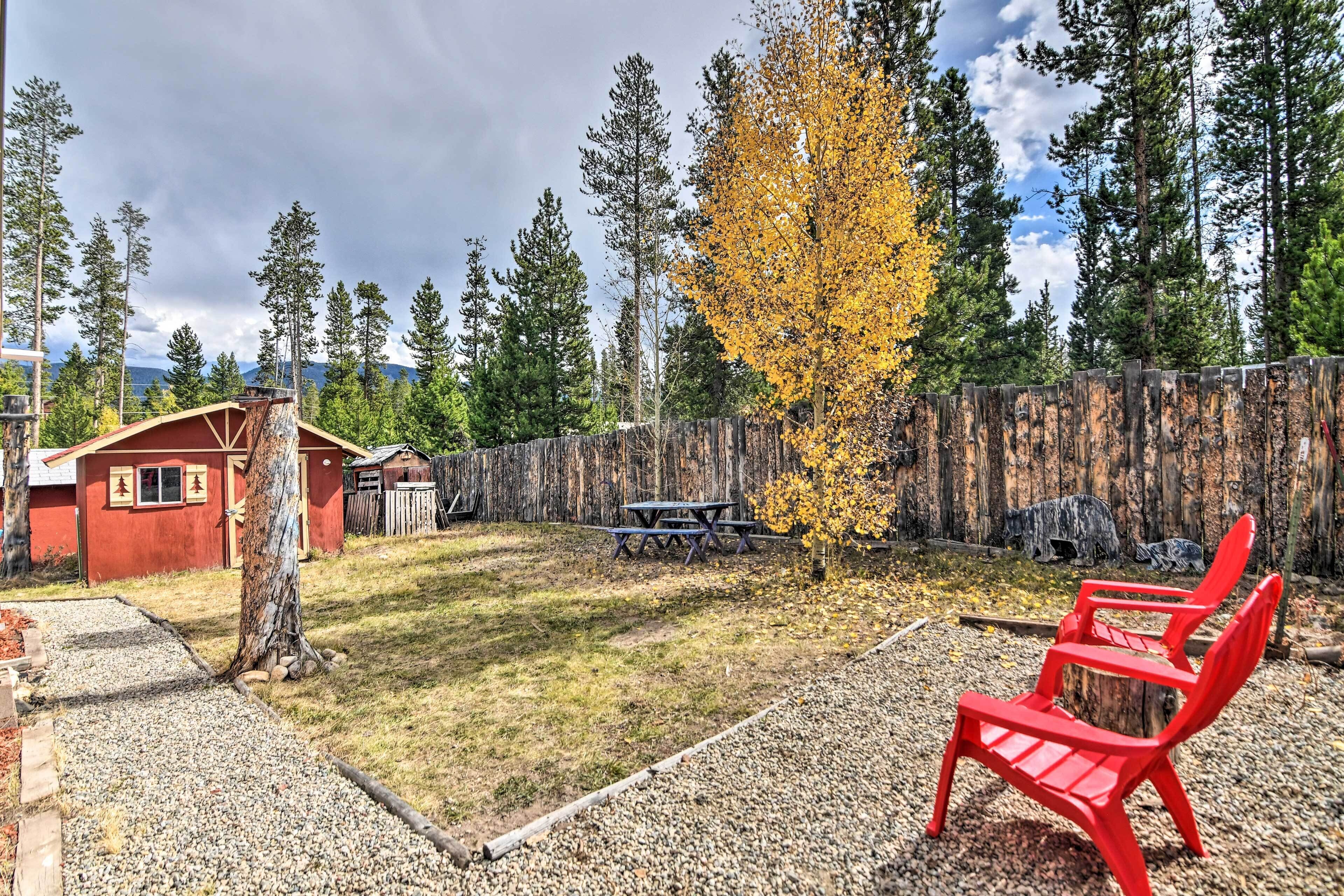 A backyard with a red building, a picnic table, and a red chair.