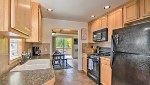 A modern kitchen with wooden cabinets, a black refrigerator, a stove, and a microwave.