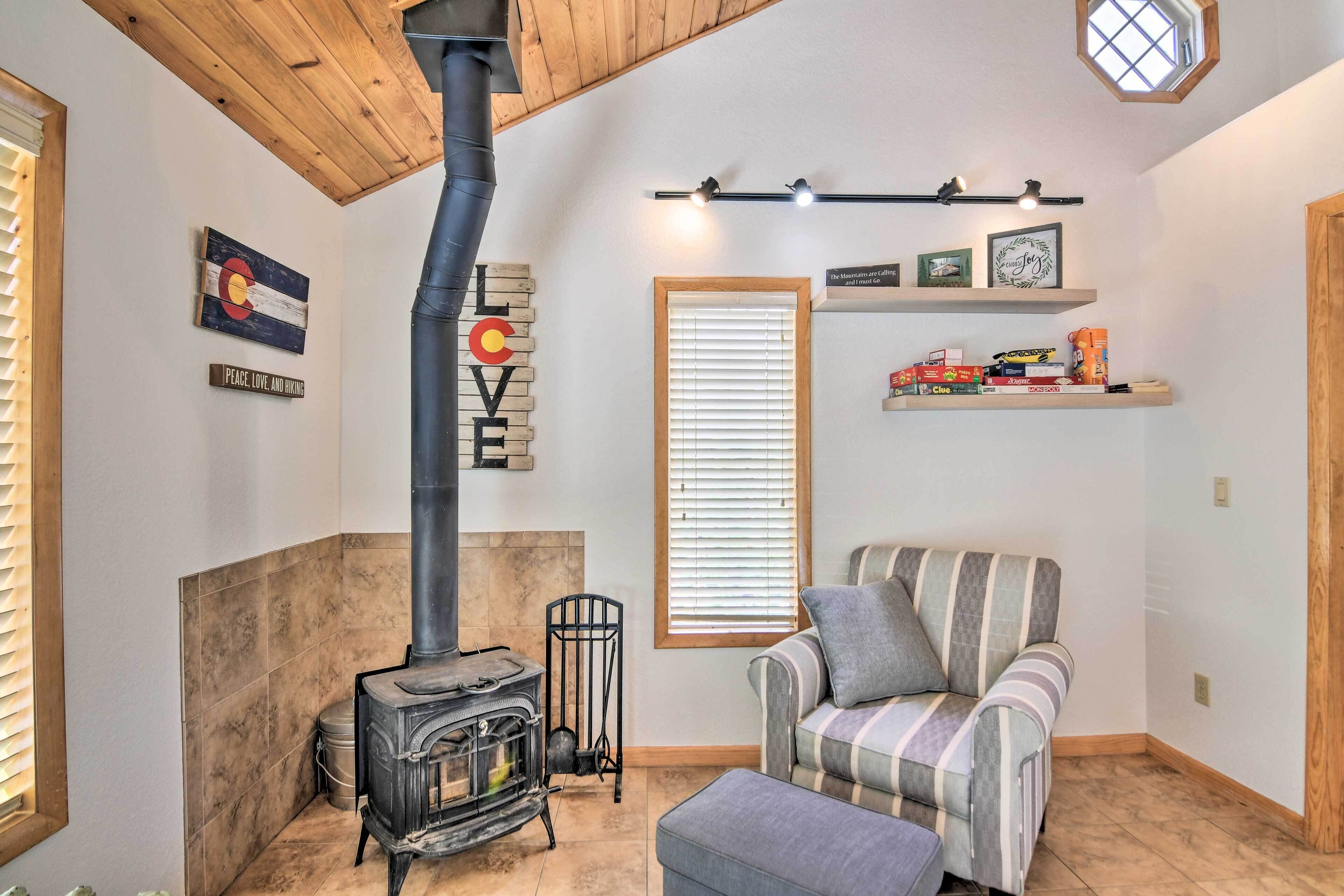 A cozy room with a wood-burning stove, a striped armchair, and a shelf with books and decorative items.