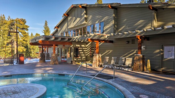 Un espace piscine doté d’un jacuzzi, d’une terrasse en bois et d’un bâtiment avec de grandes fenêtres.
