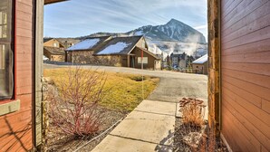 A view from a wooden building with a stone foundation, leading to a street with houses and a mountain in the background. - Crested Butte Townhome w/ Views - Steps to Lifts! (Crested Butte)