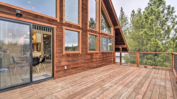 Eine Holzterrasse mit einer Glastür, die zu einem Essbereich im Innenbereich führt.
