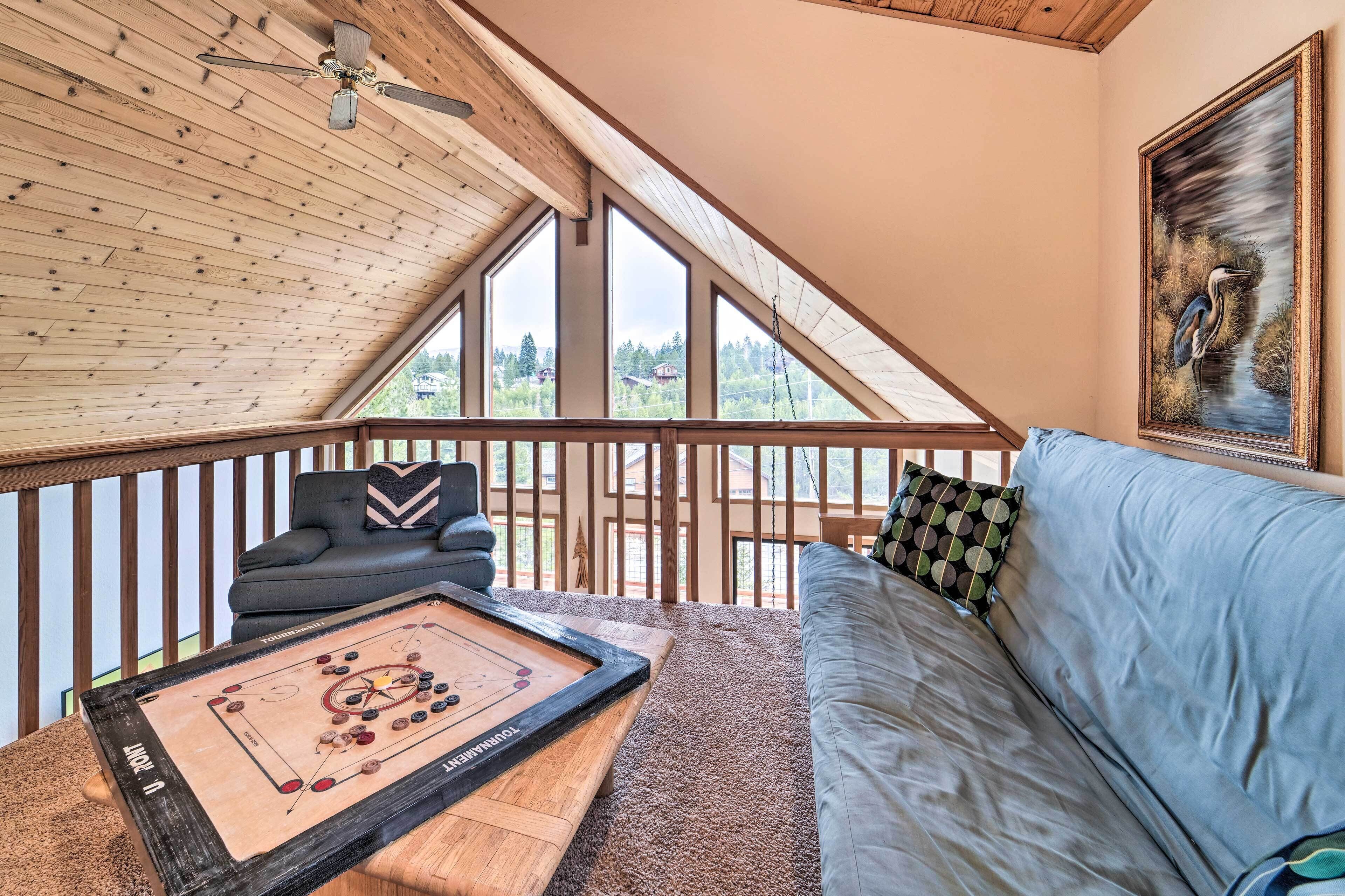 Une pièce chaleureuse avec un plafond en bois, une grande fenêtre, un canapé et une table de jeu de palet.