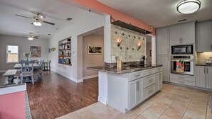 Una cocina amplia con una isla central, electrodomésticos integrados y un comedor con una mesa y sillas de madera.