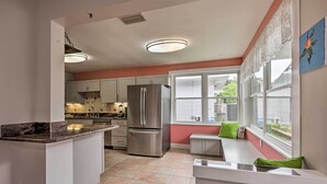 Una cocina moderna con una isla central, electrodomésticos de acero inoxidable y vistas al exterior a través de grandes ventanales.