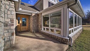 A house with a stone facade, a wooden front door, and large windows. - Grand Tulsa Getaway With Private Pond, Dock & Deck (Tulsa)