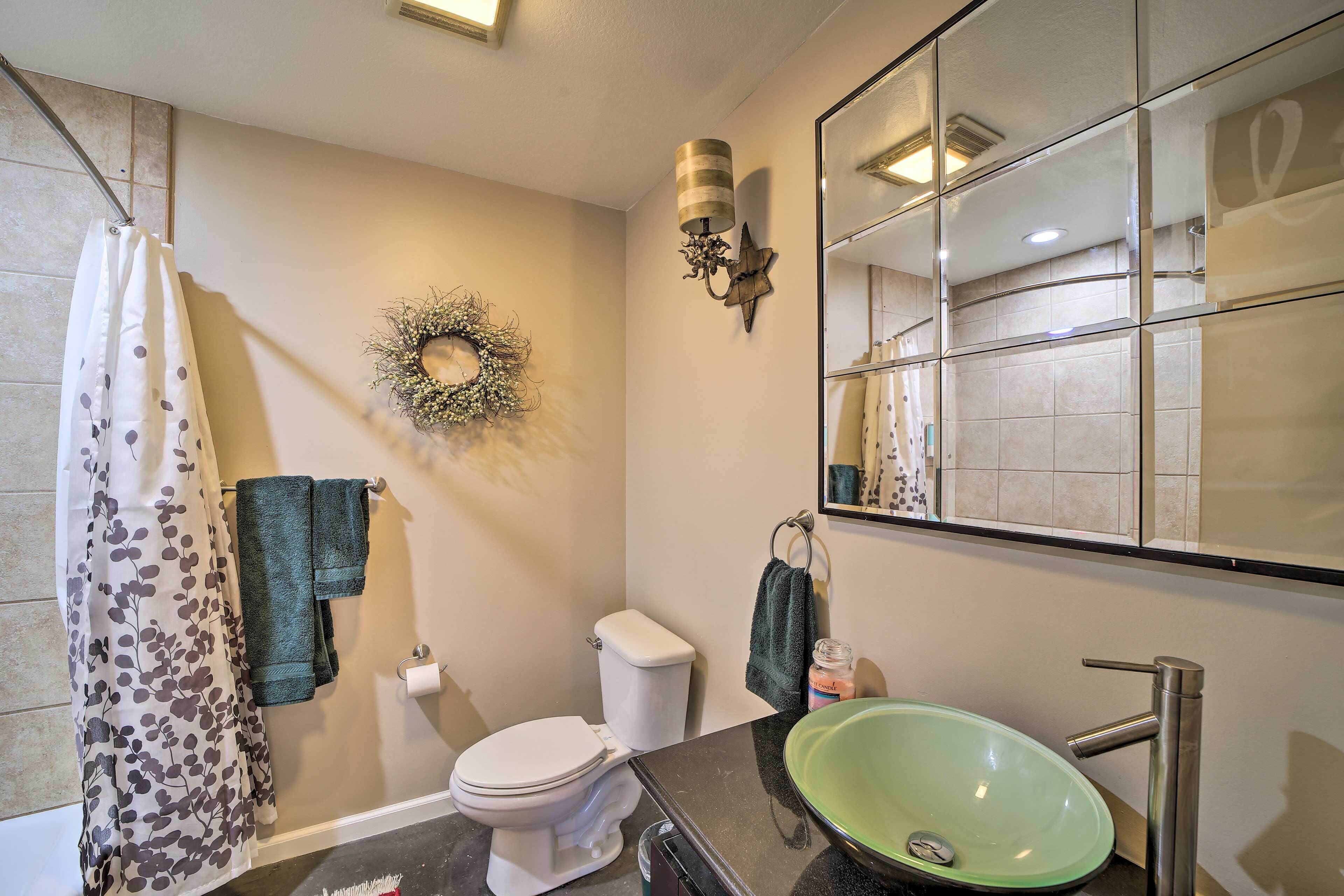 A bathroom with a toilet, green sink, shower curtain, and a mirror.
