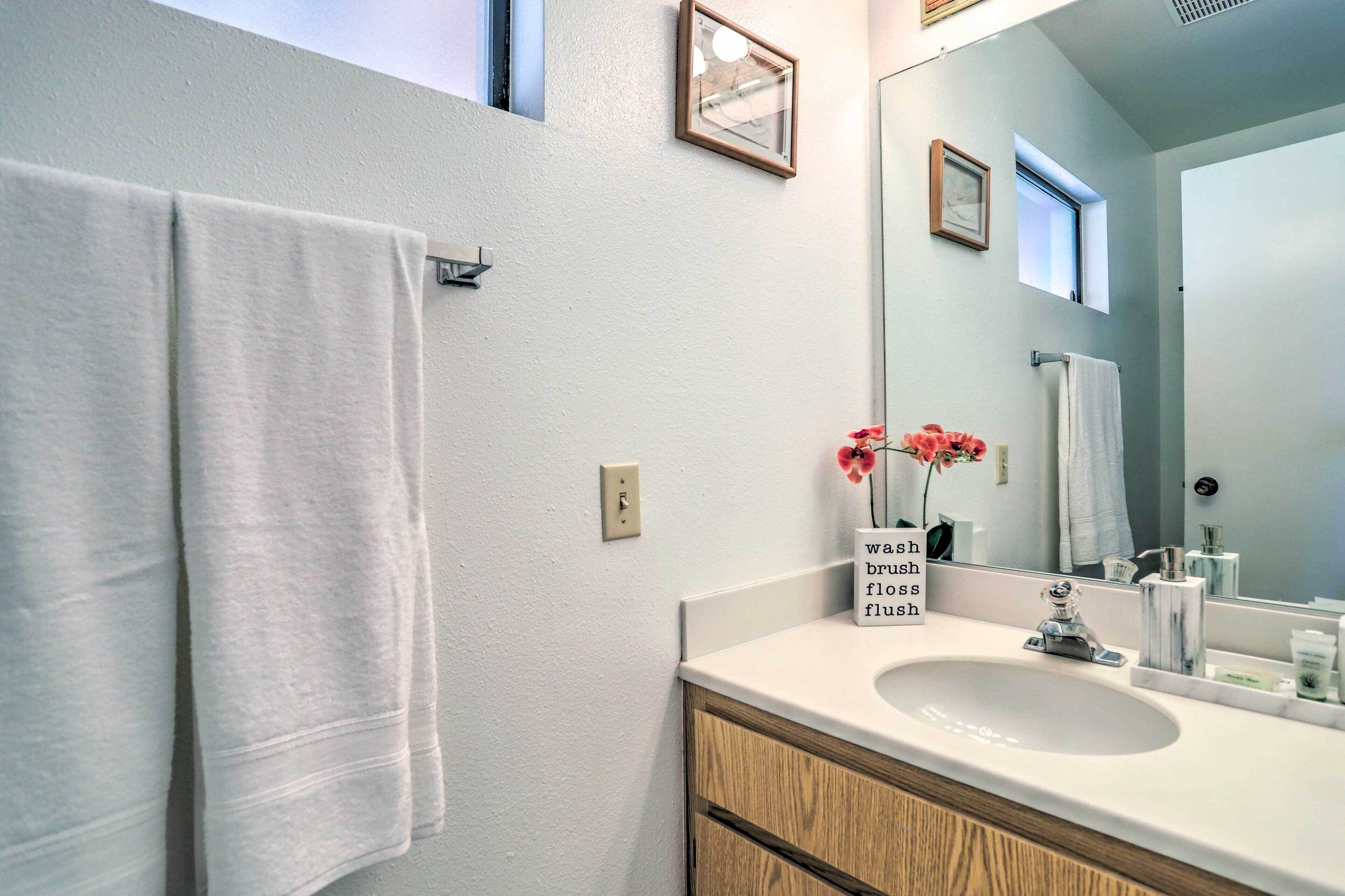 A bathroom with a white sink, wooden cabinets, a mirror, and a towel rack.