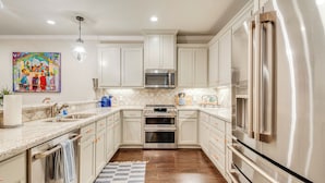 A modern kitchen with white cabinets, stainless steel appliances, and a tiled backsplash. - Gorgeous College Station Townhome w/ Patio! (College Station)