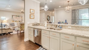 A modern kitchen with white cabinetry, a stainless steel dishwasher, and pendant lighting. - Gorgeous College Station Townhome w/ Patio! (College Station)