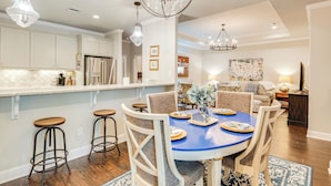 A modern kitchen with white cabinets, a blue dining table, and a chandelier. - Gorgeous College Station Townhome w/ Patio! (College Station)