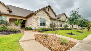 A residential house with a stone facade, a well-maintained lawn, and a landscaped front yard with a pathway. - Gorgeous College Station Townhome w/ Patio! (College Station)