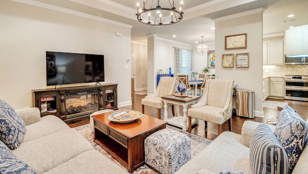 A spacious living room with a large flat-screen TV, a wooden coffee table, and comfortable seating. A dining area with a table and chairs is visible in the background. - Gorgeous College Station Townhome w/ Patio! (College Station)