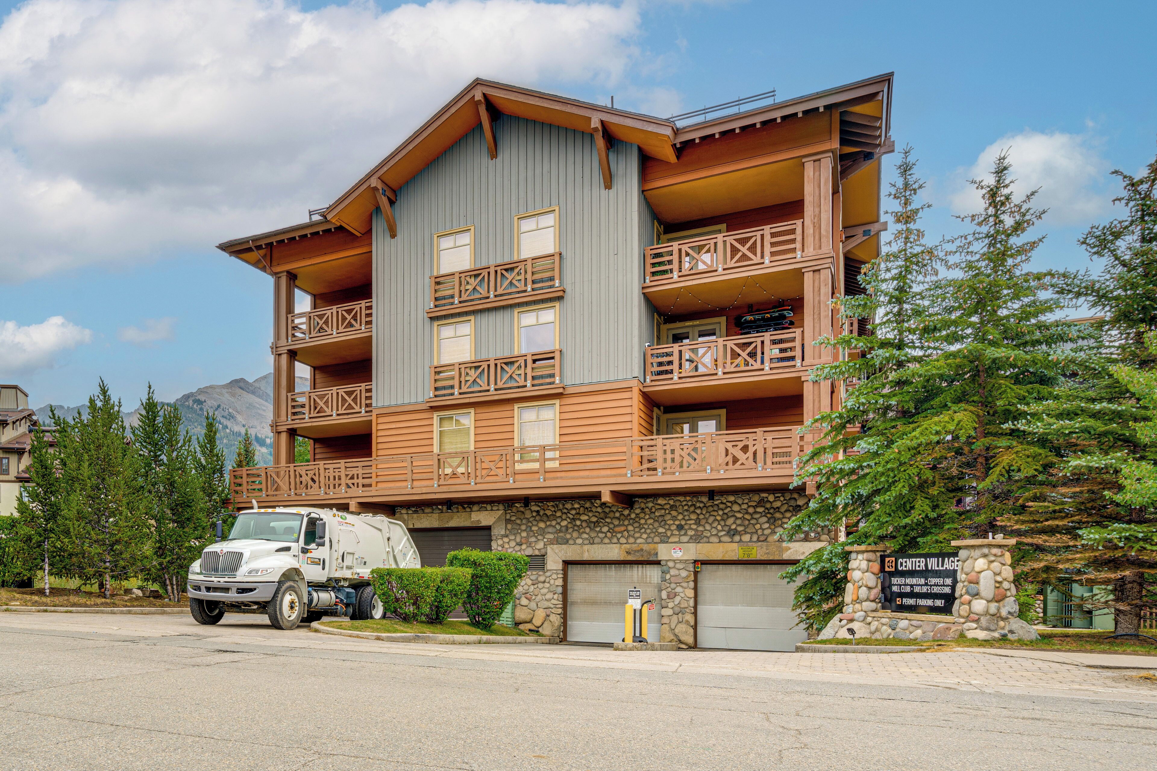 A multi-story building with balconies, a parking area, and a sign indicating it is a lodging facility.