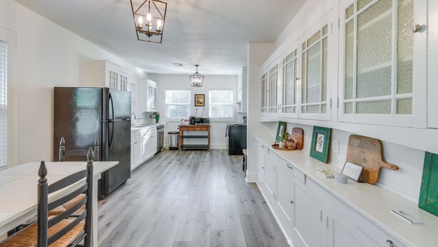 A modern kitchen with white cabinetry, a black refrigerator, and a wooden dining table. - 3 Mi to Baylor U: Home w/ Shared Yard (Waco)